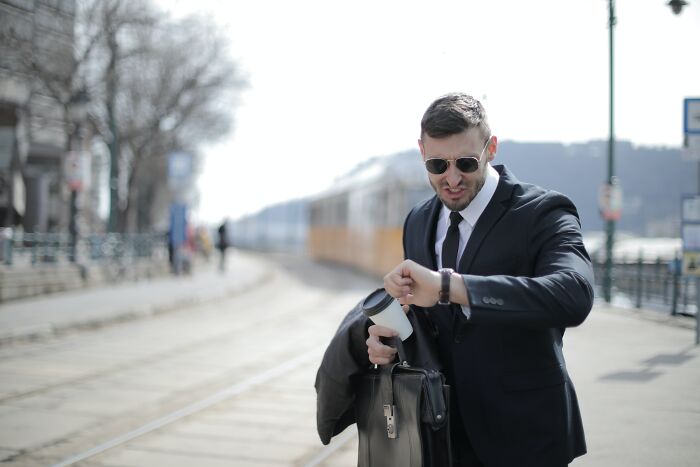 Man wearing black suit looking at his watch