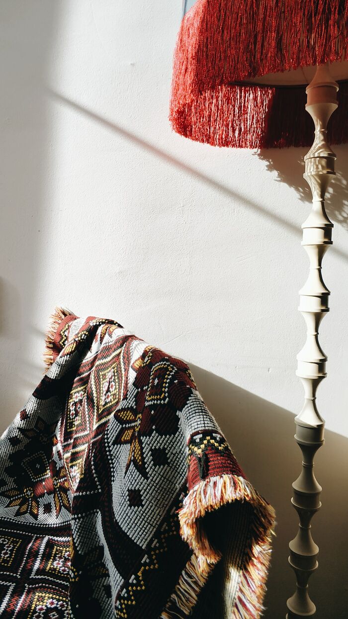 Creative inspiration in home decor with patterned throw and ornate floor lamp casting shadows.