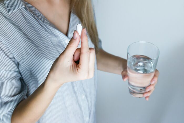 Person drinking water with pill