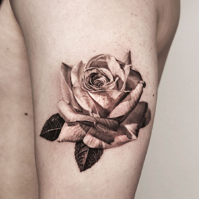 Realistic tattoo of a detailed rose on a person's arm.