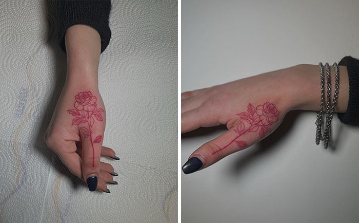 Red ink tattoo of a floral design on a person's hand, showing intricate rose patterns.
