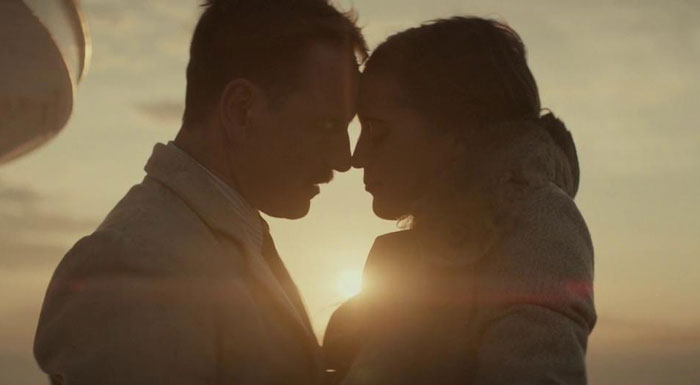 Isabel and Tom are about to kiss in front of the sunset 