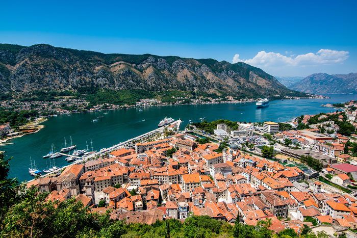 Boats in the sea, buildings with orange roofs on the shore 