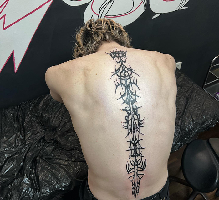 Black abstract neo-tribal tattoo on man's spine