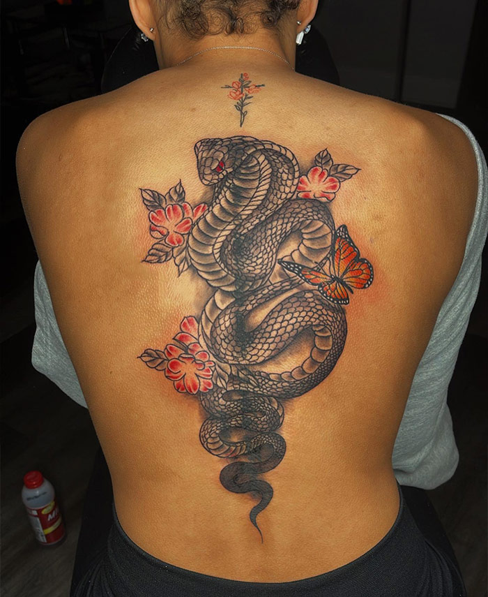 Elegant spine tattoo featuring a detailed snake with flowers and a butterfly design.