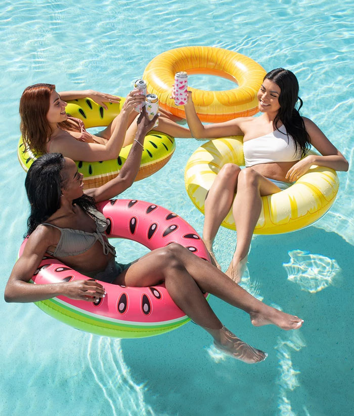 Women in the pool floats drinking beverage 