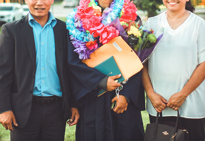 photo of a man wearing an academic gown together with his parents photo of a man wearing an academic gown together with his parents