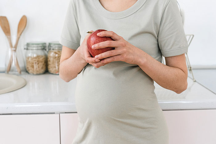 a pregnant woman with an apple