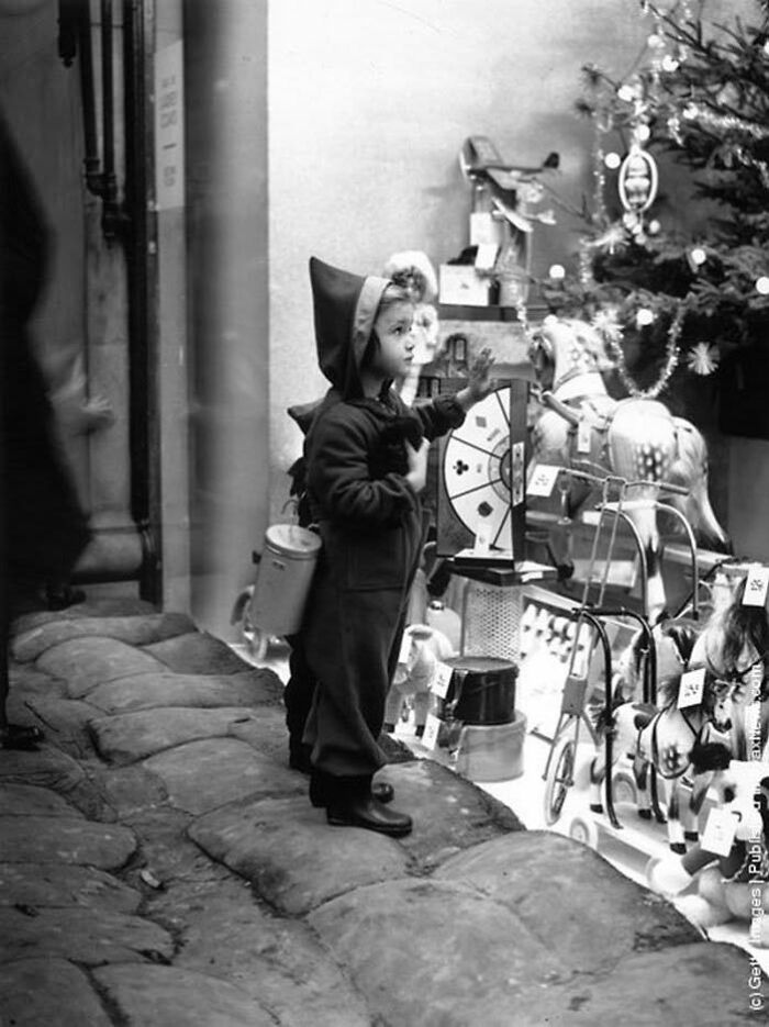 A Young Shopper Climbs On To The Sandbags To Get A Closer Look At The Toys In A Shop Window In The West End Of London, December 1939
