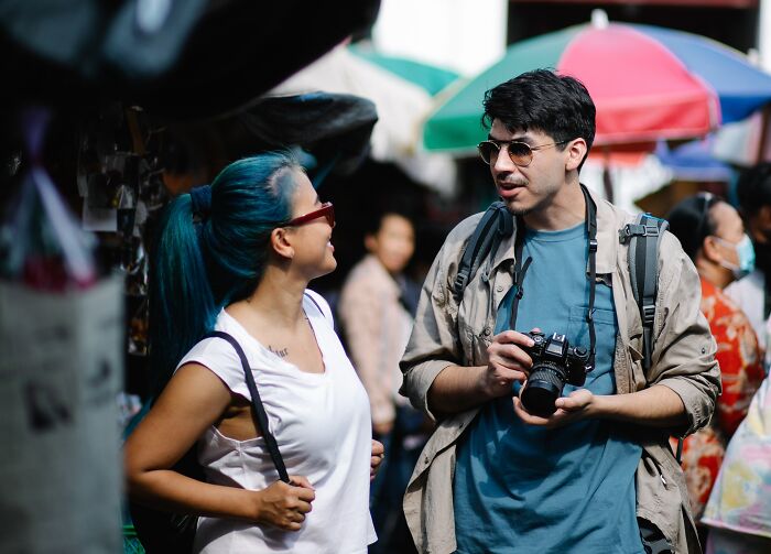 A man with camera talks to a woman 