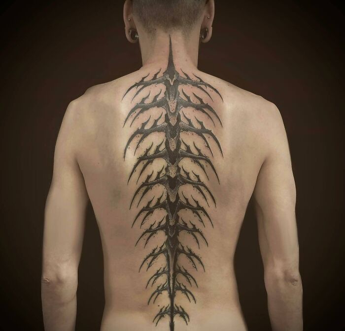 A person with an elegant spine tattoo design covering their back.
