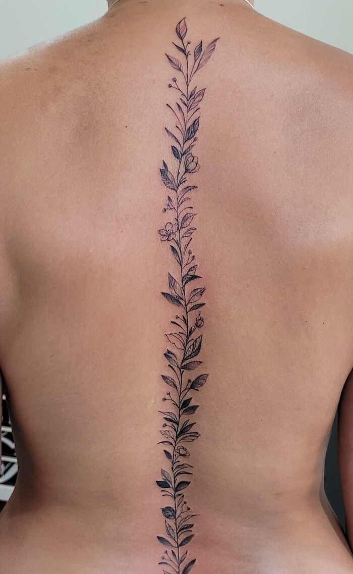 Small flowers and leaves along the spine tattoo 