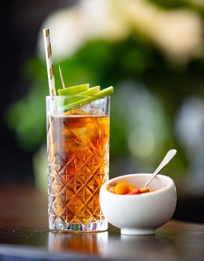 a glass of tea with a straw and pieces of limes
