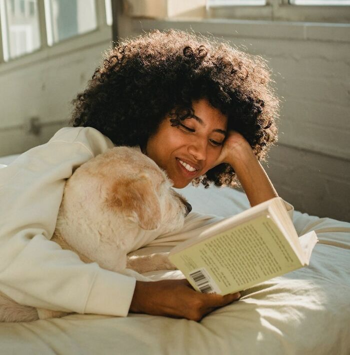 woman reading the book with her dog