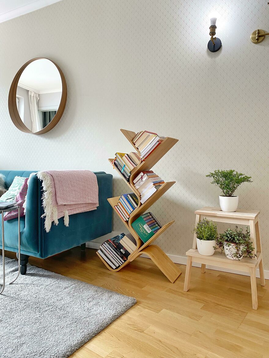 Book shelf with books next to a green couch 