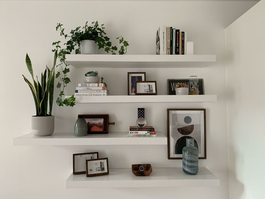 White book shelfs with books and plants on it 