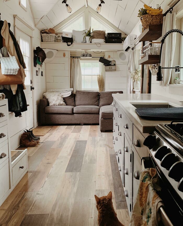 Cozy tiny house interior with loft, modern kitchen, and a sofa, capturing the warmth and charm of tiny house designs.
