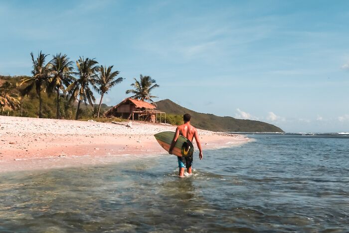 Man walking with a surfboard in the beach 
