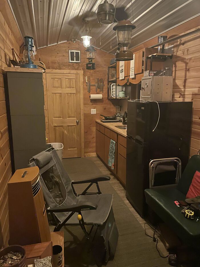 Cozy brown tiny house kitchen featuring wood paneling and a compact black fridge for efficient small space living.