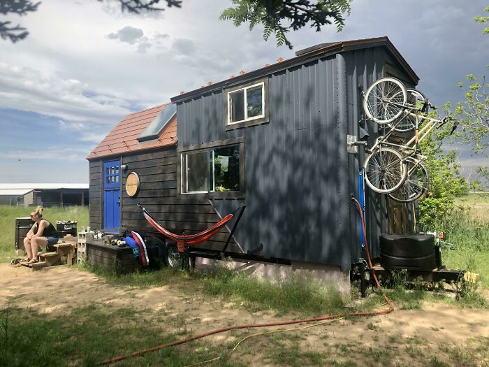 Black small house with bicycles attached to its' wall 