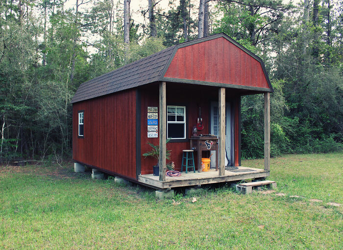 Red small house in a forest setting showcasing tiny house designs that inspire building a compact home.