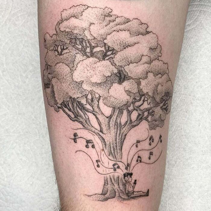 Tattoo with man sitting under tree and listening to music