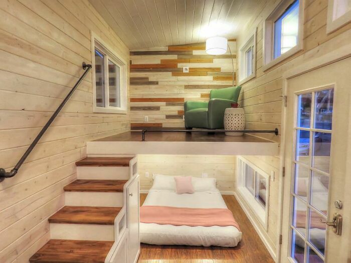 Cozy tiny house interior with wood accents, loft seating, and minimalist bedding.