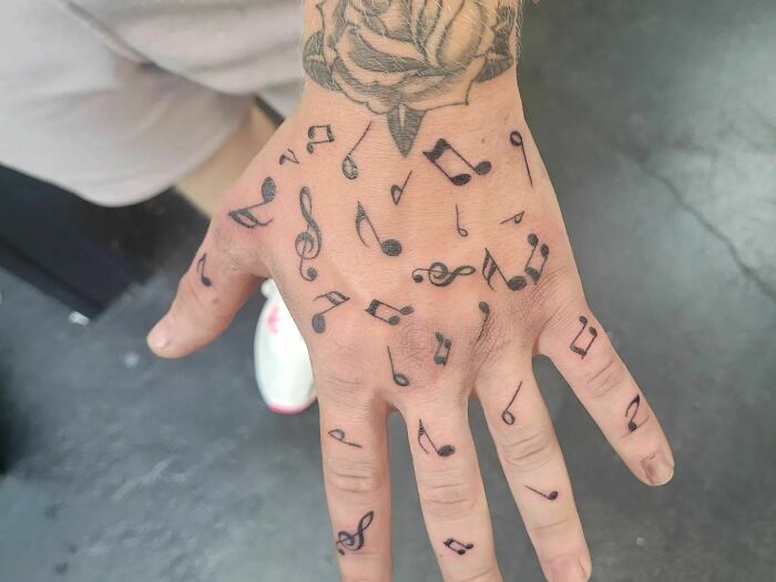 Many small black notes tattoos on a hand