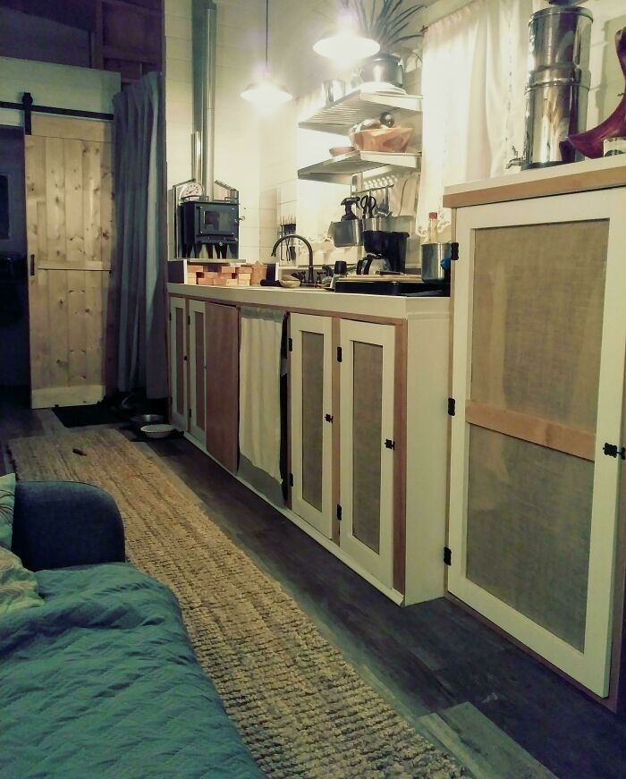 Cozy tiny house kitchen featuring white and brown cabinets, compact layout, and warm ambient lighting for small living spaces.
