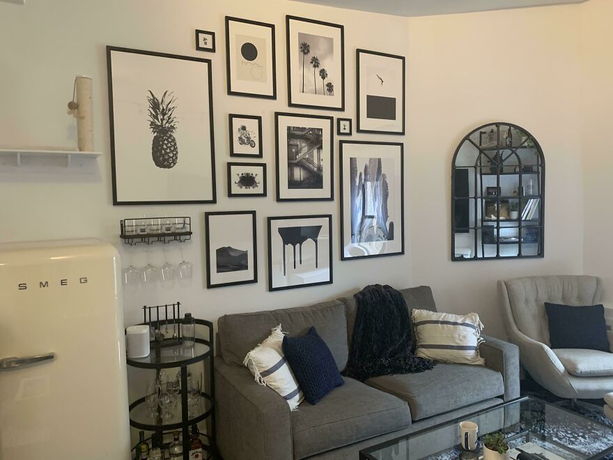 Grey couch with pillows, black and white photos on the wall 