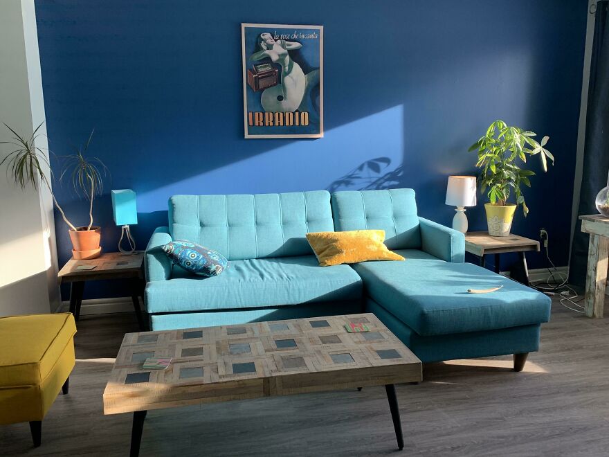 Blue couch with yellow pillow on it 