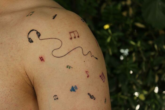 Small musical notes and headphones tattoo on shoulder