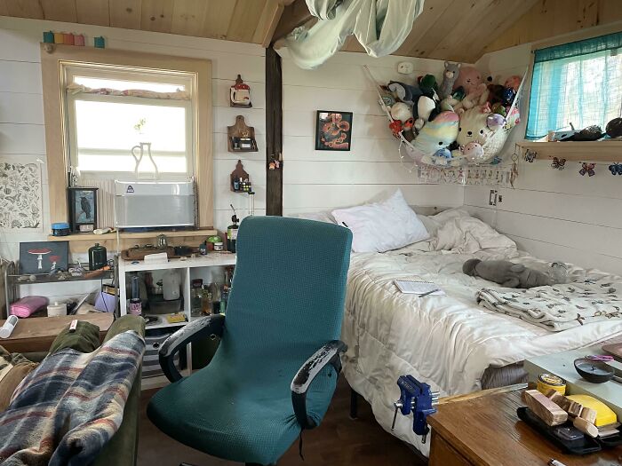 Cozy tiny house interior with bed, teal chair, and decorations, showcasing smart space utilization.