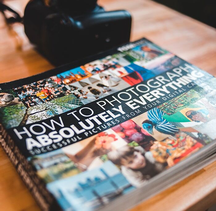 Colorful book with pictures near photo camera on table