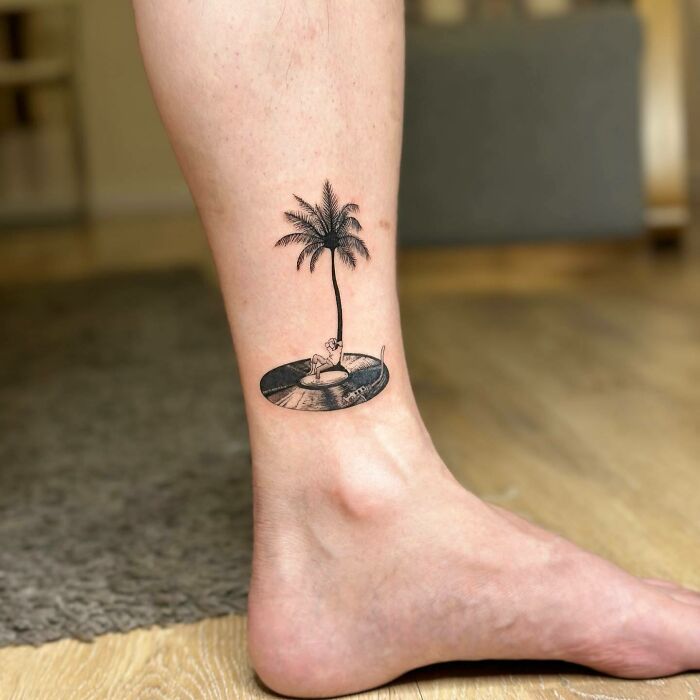 Leg tattoo with boy, vinyl and palm tree