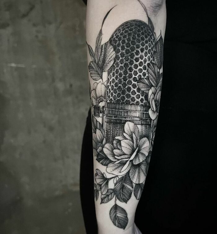 Black realistic microphone and flowers tattoo on arm