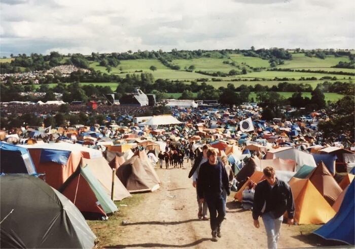Area with many tents and people walking at Glastonbury Festival, 1990
