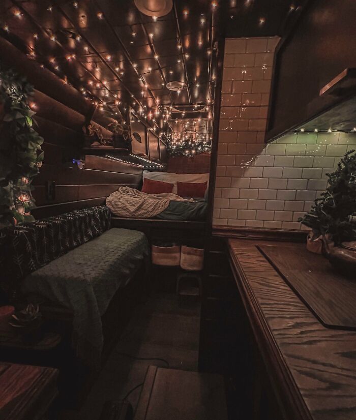 Cozy brown tiny house interior featuring string lights on the ceiling, wooden surfaces, and a compact living space.