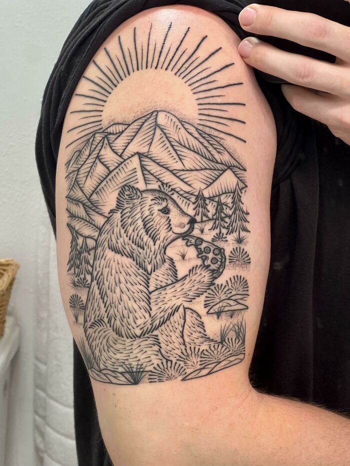 A bear eating pizza in the mountains arm tattoo