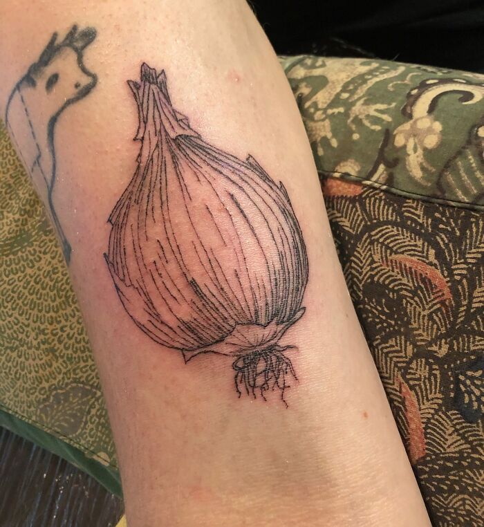 Black and white onion tattoo on forearm, showcasing unique food ink-spiration.