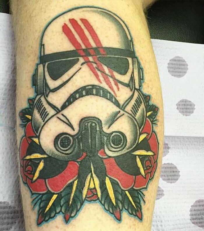 American traditional tattoo of a helmet with red roses and leaves, featuring bold lines and vibrant colors.