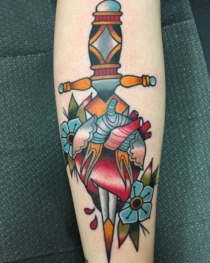 American traditional tattoo featuring a dagger piercing a heart with flowers.