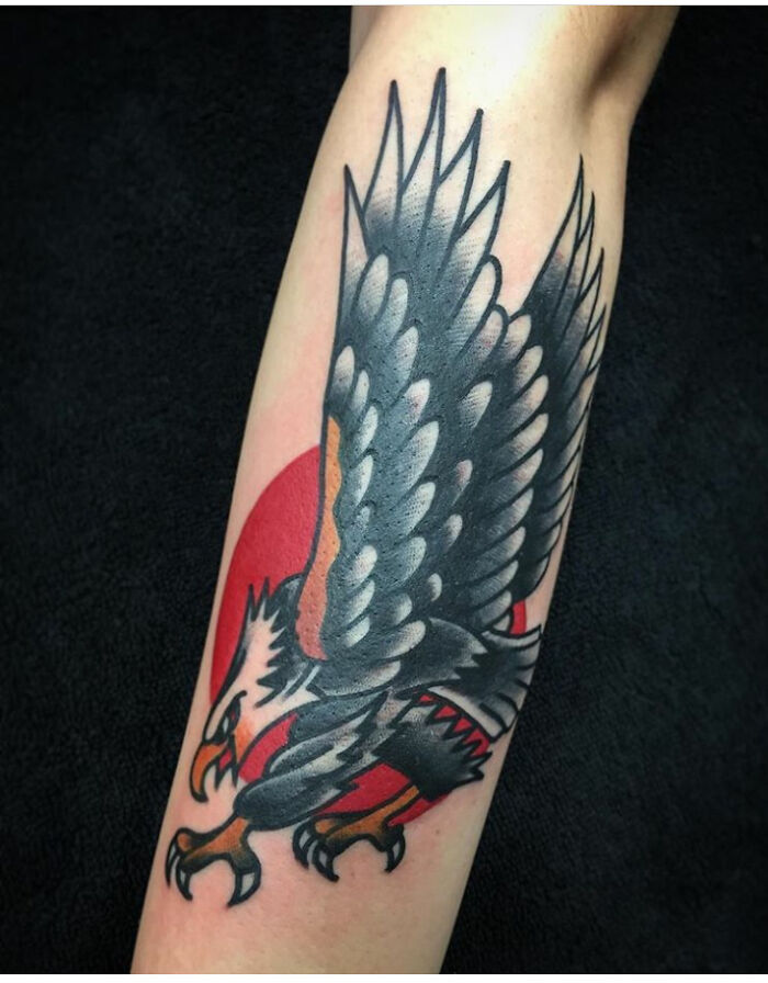 American traditional tattoo of an eagle with bold colors and sharp lines on a forearm.