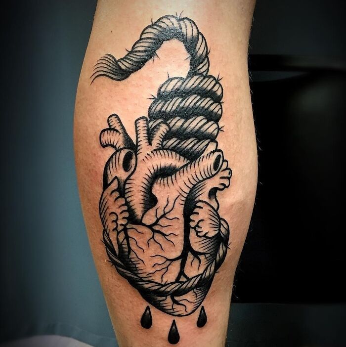 American traditional tattoo of a heart with a rope, shaded in black ink, on a person's calf.