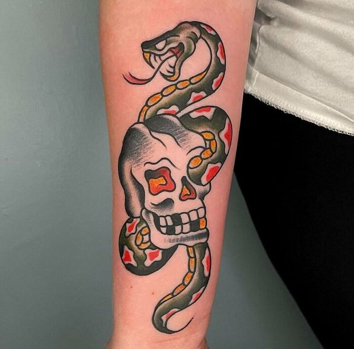 Snake and skull American traditional tattoo on forearm, showcasing bold colors and classic design.