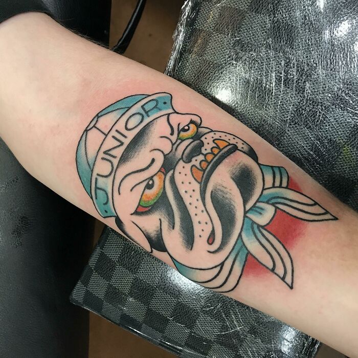 American traditional tattoo of a bulldog wearing a hat and bandana on an arm.