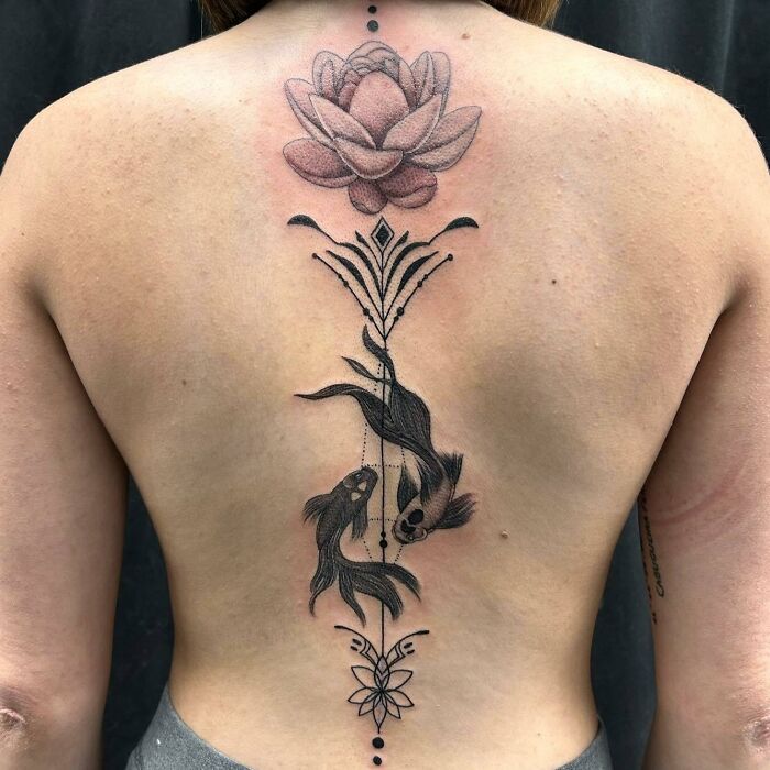 Spine tattoo featuring a pink lotus and two koi fish, showcasing intricate design along the back.