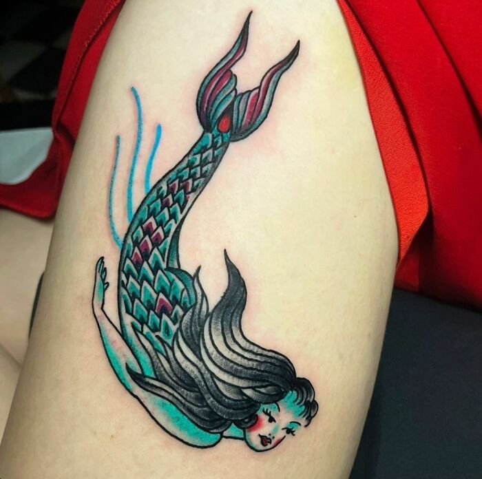 American traditional tattoo of a colorful mermaid on a person's arm.