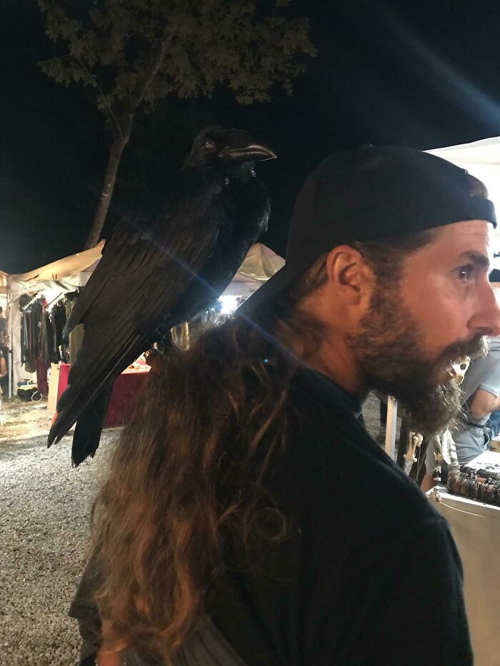 Man standing and having crow on his back