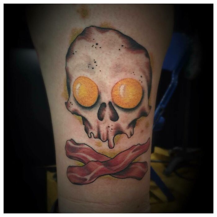 Watercolor skull tattoo with eggs and bacon design, showcasing creative food ink-spiration.